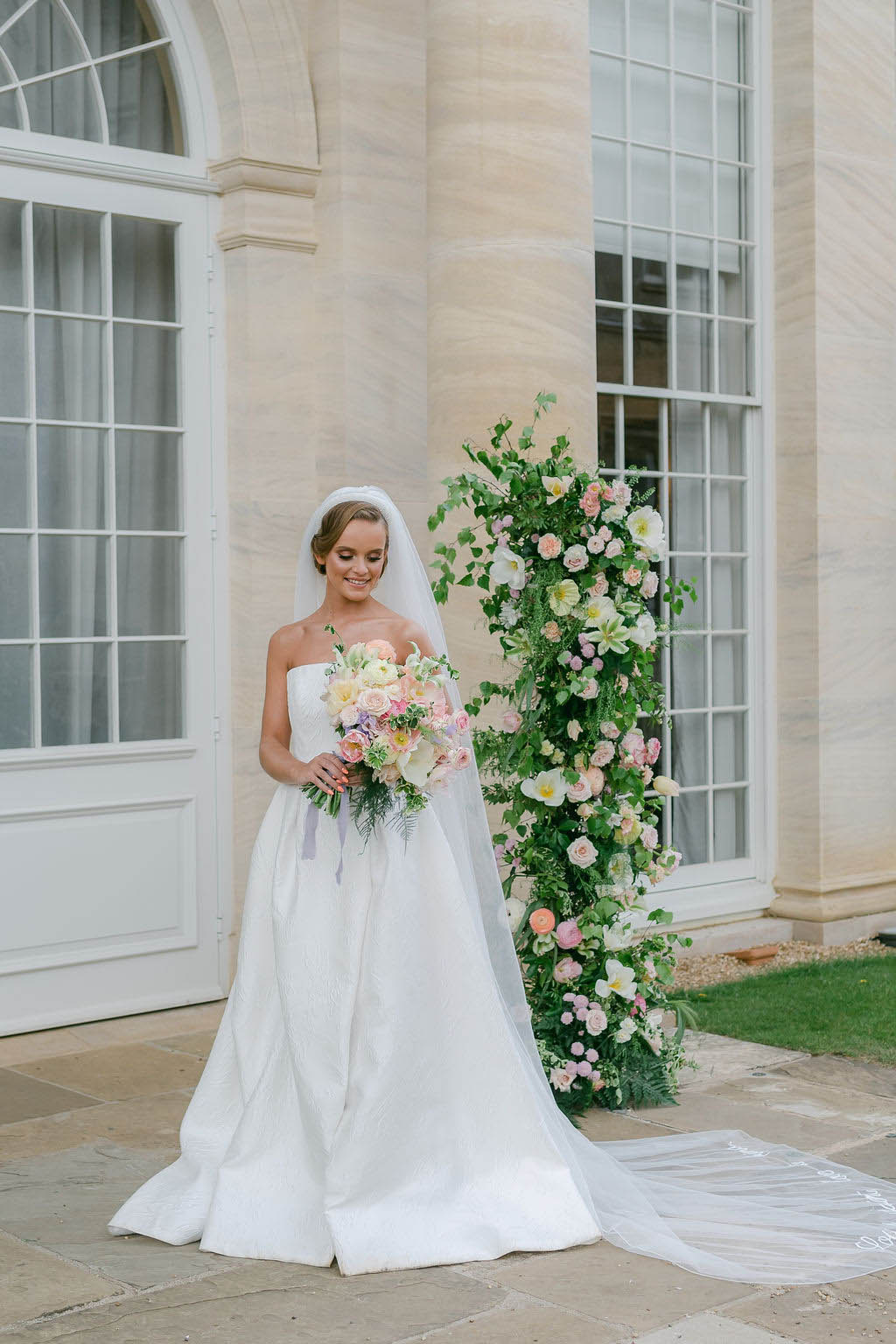 A bride holding a pastel wedding bouquet outside a venue