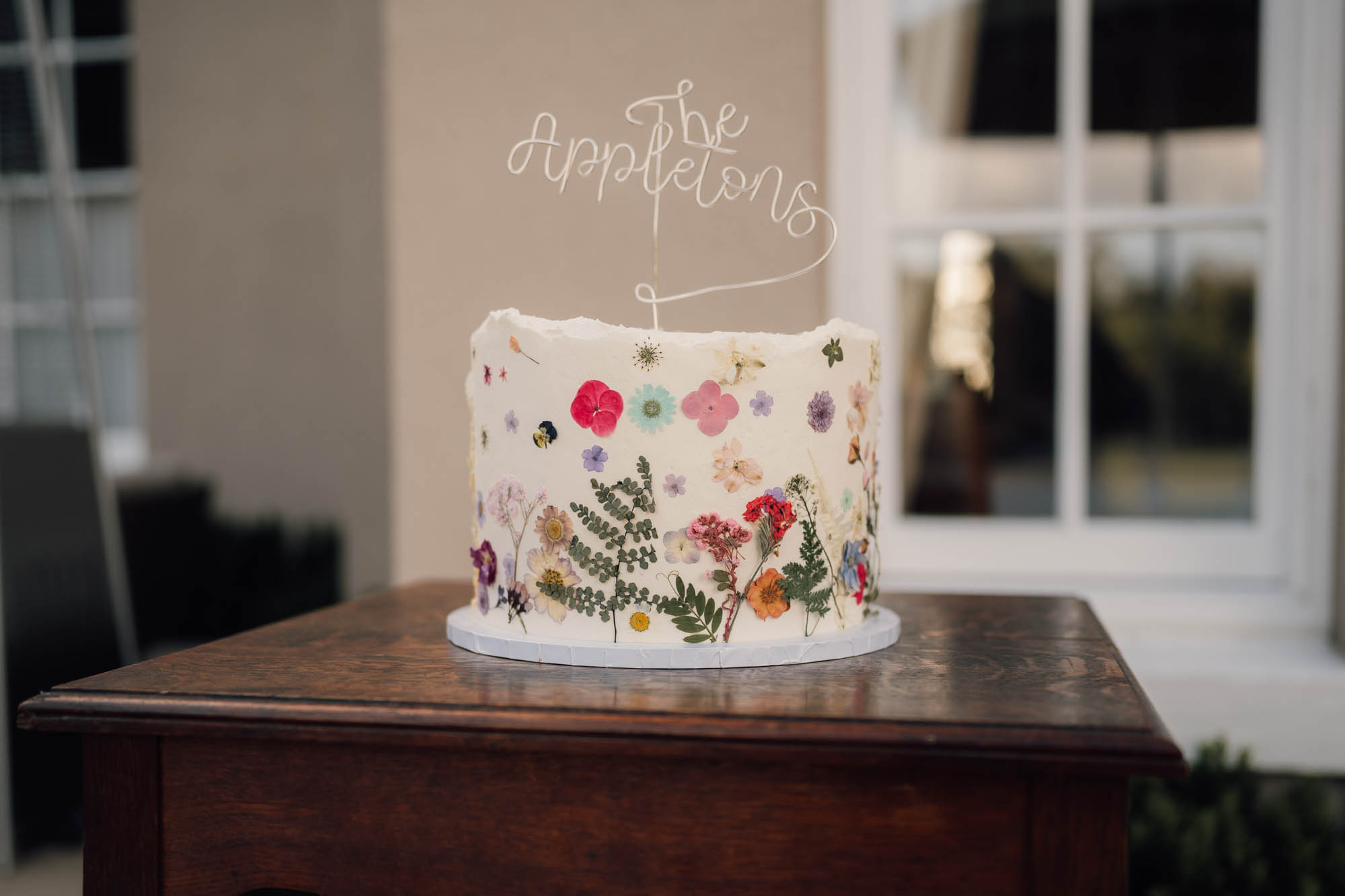 pretty single tier wedding cake with pressed wildflowers